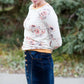 Woman wearing a long denim skirt without a slit that has buttons up the front and is a flare, a-line style.