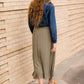 Woman wearing a lightweight ankle-length olive skirt with buttons up the front.