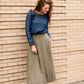Woman wearing a lightweight ankle-length olive skirt with buttons up the front.