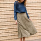 Woman wearing a lightweight ankle-length olive skirt with buttons up the front.