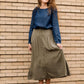 Woman wearing a lightweight ankle-length olive skirt with buttons up the front.