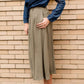 Woman wearing a lightweight ankle-length olive skirt with buttons up the front.