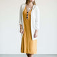 Woman wearing a ribbed mustard midi dress with faux wood buttons.