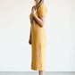Woman wearing a ribbed mustard midi dress with faux wood buttons.