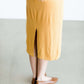 Woman wearing a ribbed mustard midi dress with faux wood buttons.