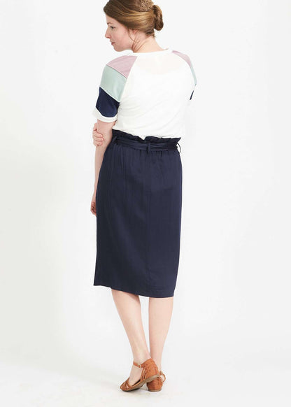 Woman wearing a navy button front paper bag style midi skirt.