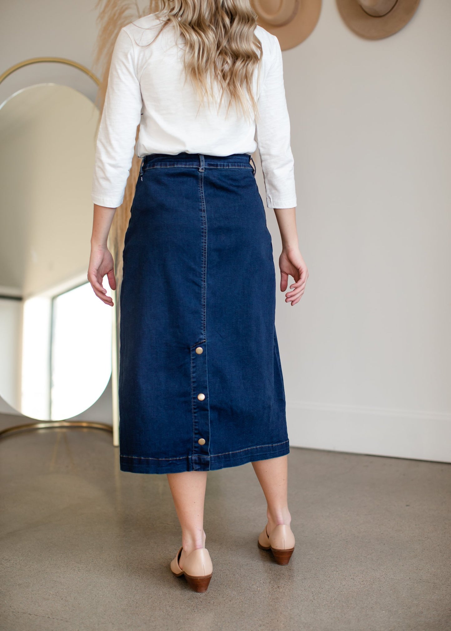 The caren skirt is an inherit design with functioning side pockets and is a slight a-line denim skirt. It has matte gold buttons on the back for added detail.