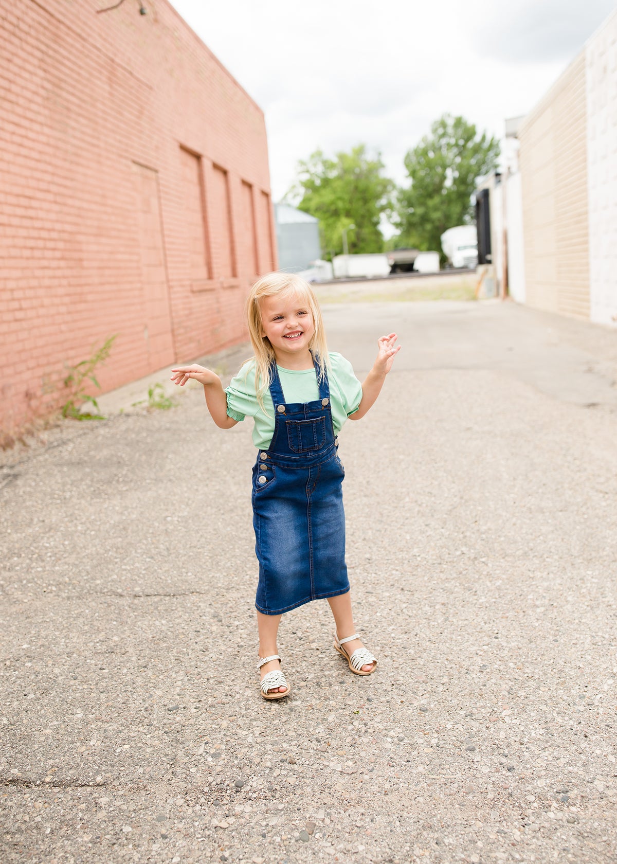 young girl in overall denim jumper dress