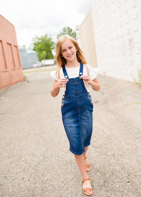 young girl in overall denim jumper dress