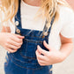 young girl in overall denim jumper dress