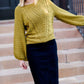 Young woman wearing a balloon sleeve chenille like sweater with a below the knee navy midi skirt