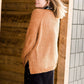 Woman wearing an open front cardigan that is chenille and camel in color. She is also wearing it over a black dress and brown riding boots. She is standing on the stairs at Inherit Clothing Company.