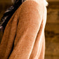 Woman wearing an open front cardigan that is chenille and camel in color. She is also wearing it over a black dress and brown riding boots. She is standing on the stairs at Inherit Clothing Company.