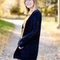 Young girl wearing a navy long chenille sweater with front pockets and a cozy fit