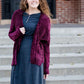 Woman wearing a wine colored shrug chenille sweater with open front and extra length in the back.