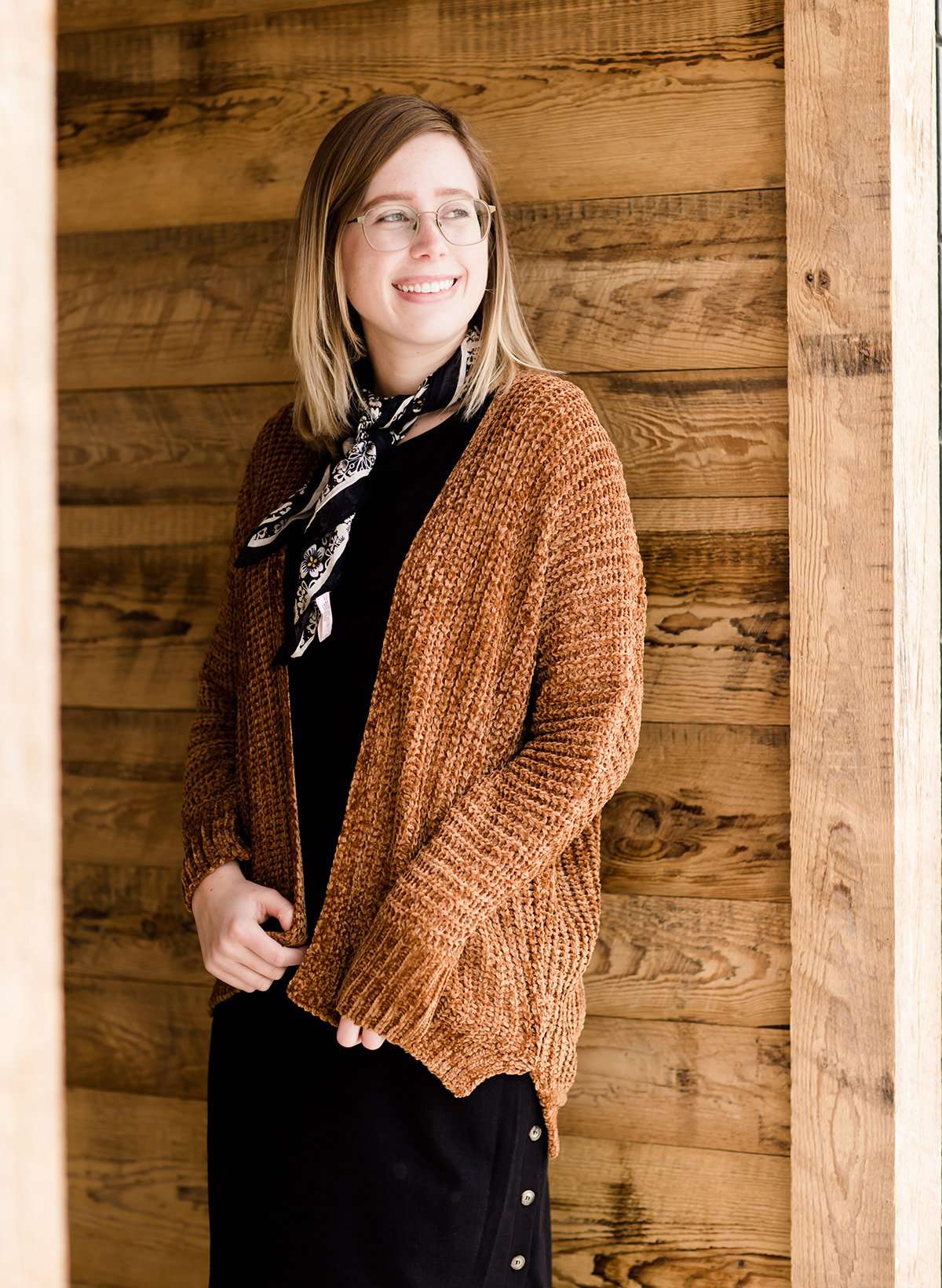 Woman wearing a caramel chenille shrug style sweater that is carmel in color. She is also wearing a black modest dress and scarf.