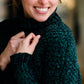 Woman wearing a dark green chenille turtle neck paired with a modest black midi skirt standing outside of Inherit Clothing Company