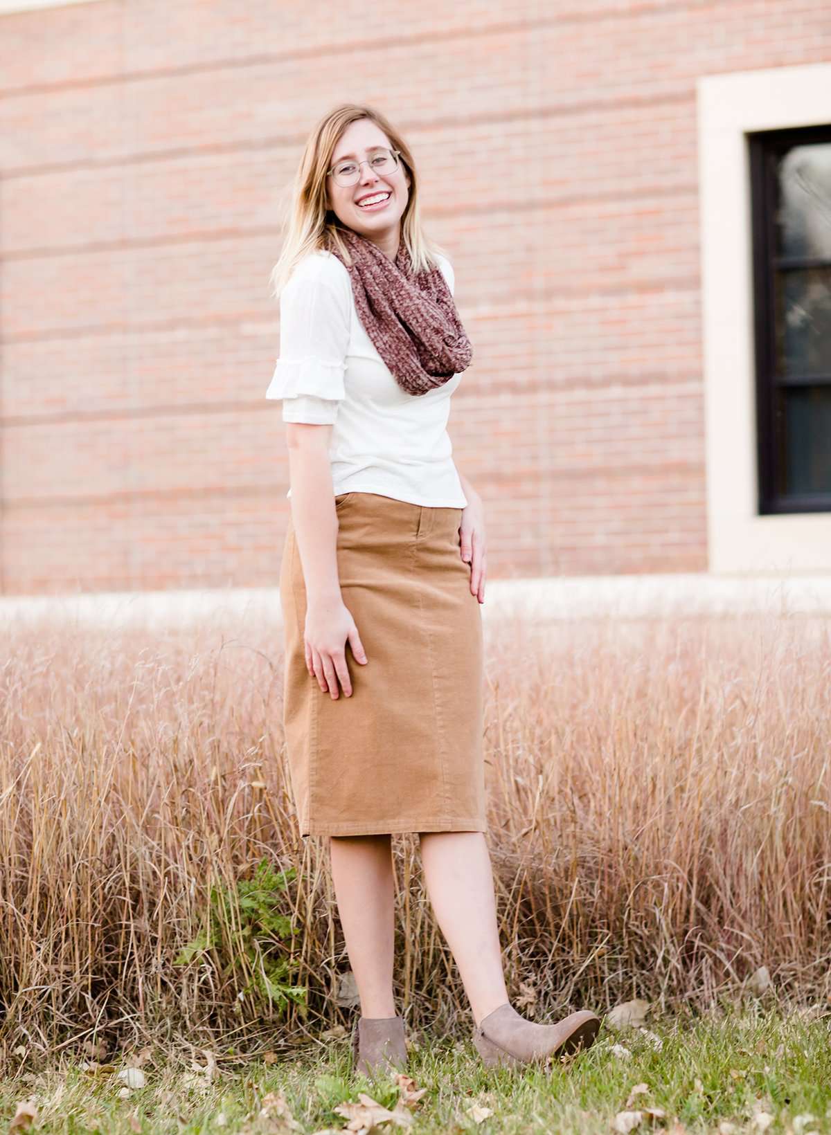 Woman wearing a chenille style snood scarf. This cowl like scarf comes in cream or taupe.