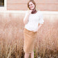 Woman wearing a chenille style snood scarf. This cowl like scarf comes in cream or taupe.