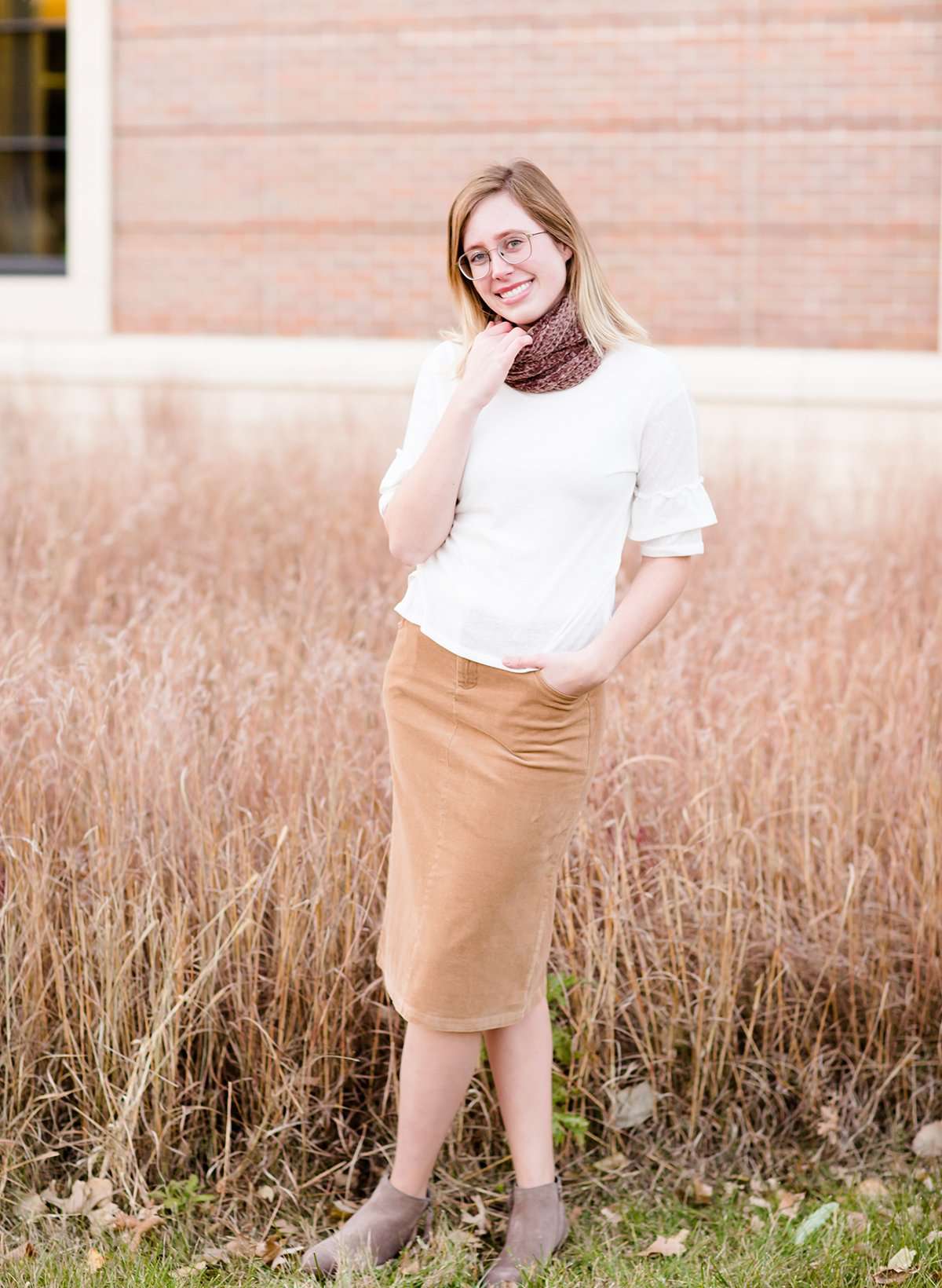 Woman wearing a chenille style snood scarf. This cowl like scarf comes in cream or taupe.