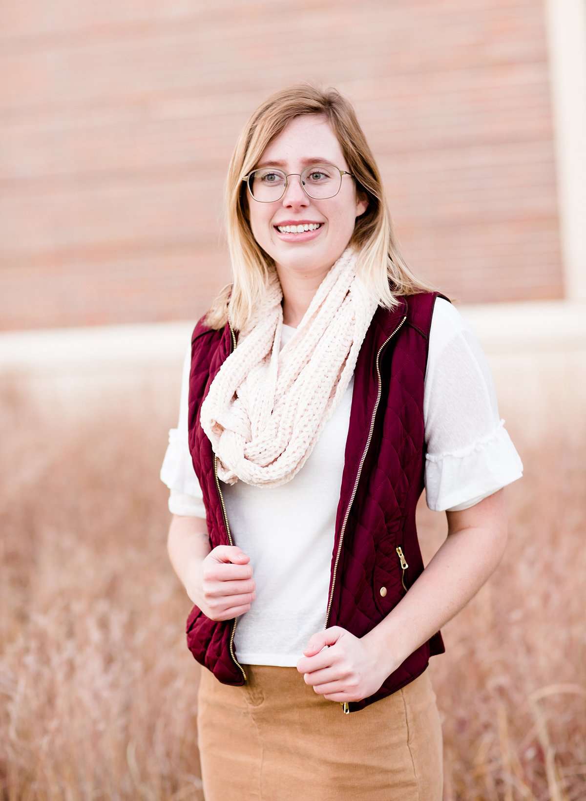 Woman wearing a chenille style snood scarf. This cowl like scarf comes in cream or taupe.