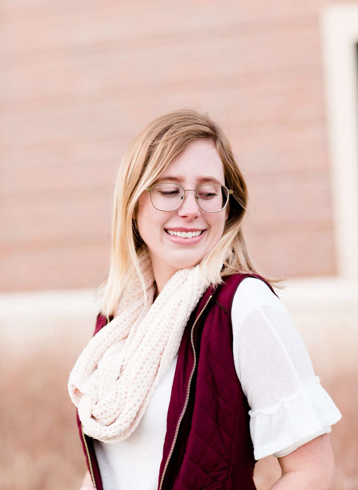 Woman wearing a chenille style snood scarf. This cowl like scarf comes in cream or taupe.