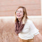 Woman wearing a chenille style snood scarf. This cowl like scarf comes in cream or taupe.