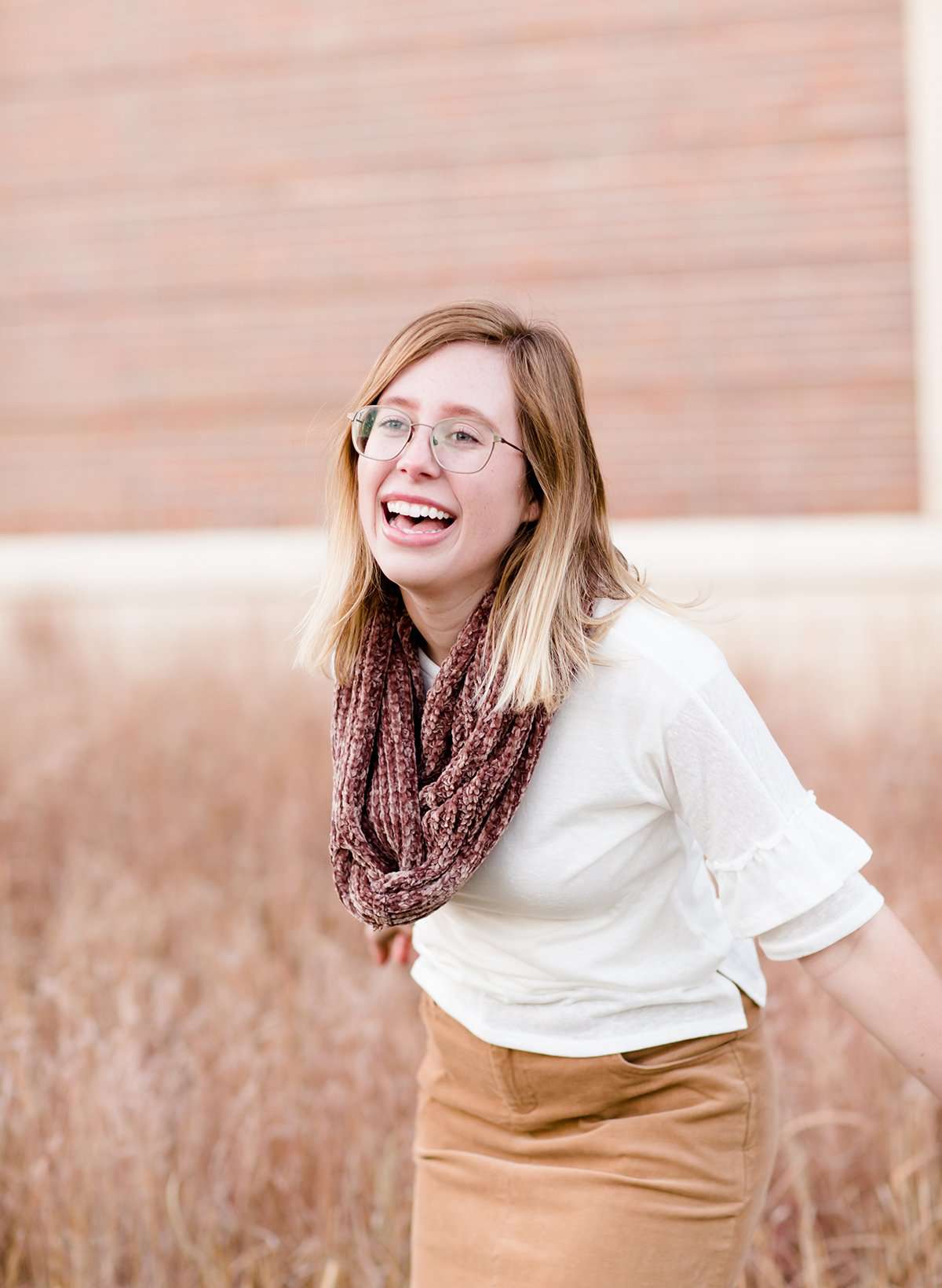 Woman wearing a chenille style snood scarf. This cowl like scarf comes in cream or taupe.