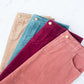 Woman wearing a below the knee corduroy skirt. This skirt is a fin corduroy with a gold button snap, no slit and no back pockets. It comes in burgundy, teal, burnt orange and dark khaki.