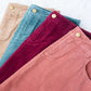 Woman wearing a below the knee corduroy skirt. This skirt is a fin corduroy with a gold button snap, no slit and no back pockets. It comes in burgundy, teal, burnt orange and dark khaki.