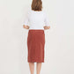 Woman wearing a below the knee corduroy skirt. This skirt is a fin corduroy with a gold button snap, no slit and no back pockets. It comes in burgundy, teal, burnt orange and dark khaki.