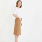 Woman wearing a below the knee corduroy skirt. This skirt is a fin corduroy with a gold button snap, no slit and no back pockets. It comes in burgundy, teal, burnt orange and dark khaki.