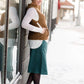Woman wearing a below the knee corduroy skirt. This skirt is a fin corduroy with a gold button snap, no slit and no back pockets. It comes in burgundy, teal, burnt orange and dark khaki.