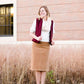 Woman wearing a below the knee corduroy skirt. This skirt is a fin corduroy with a gold button snap, no slit and no back pockets. It comes in burgundy, teal, burnt orange and dark khaki.