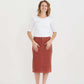 Woman wearing a below the knee corduroy skirt. This skirt is a fin corduroy with a gold button snap, no slit and no back pockets. It comes in burgundy, teal, burnt orange and dark khaki.