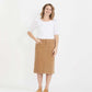 Woman wearing a below the knee corduroy skirt. This skirt is a fin corduroy with a gold button snap, no slit and no back pockets. It comes in burgundy, teal, burnt orange and dark khaki.
