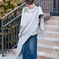 Woman wearing a gray fringe scarf that is super cozy and knit.