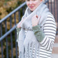 Woman wearing a gray fringe scarf that is super cozy and knit.