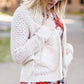 Young woman wearing a ivory chunky knit acrylic and wool sweater. This sweater has front pockets and features an open front.