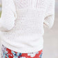 Young woman wearing a ivory chunky knit acrylic and wool sweater. This sweater has front pockets and features an open front.