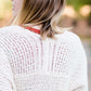 Young woman wearing a ivory chunky knit acrylic and wool sweater. This sweater has front pockets and features an open front.