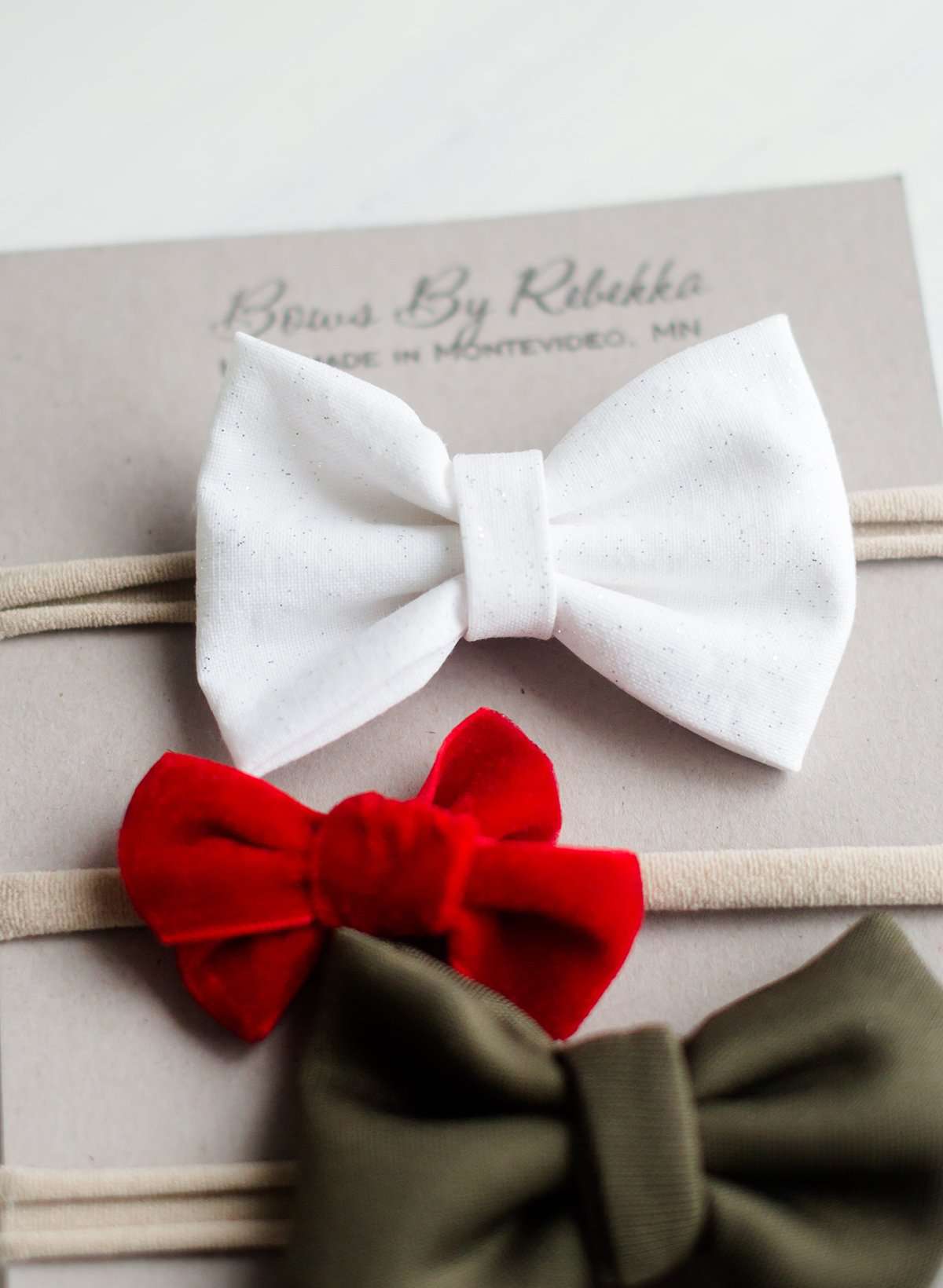 Little girls hair bow set of three. This shows a white, green and red velvet headband on a nylon band.