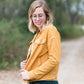 Woman wearing a mustard corduroy button down jacket with pockets.