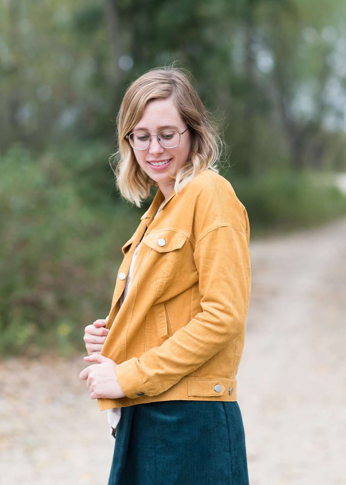 Woman wearing a mustard corduroy button down jacket with pockets.