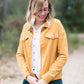 Woman wearing a mustard corduroy button down jacket with pockets.