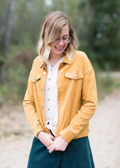 Woman wearing a mustard corduroy button down jacket with pockets.