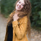 Woman wearing a mustard corduroy button down jacket with pockets.