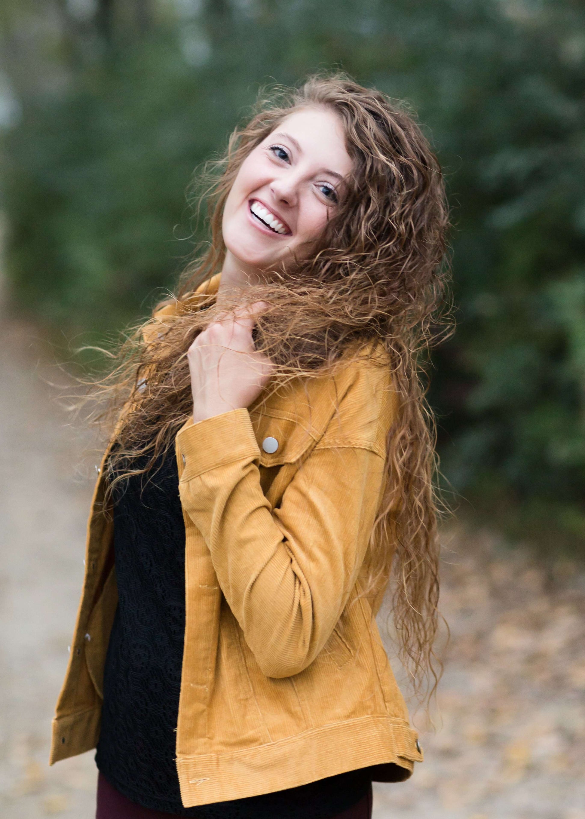 Woman wearing a mustard corduroy button down jacket with pockets.
