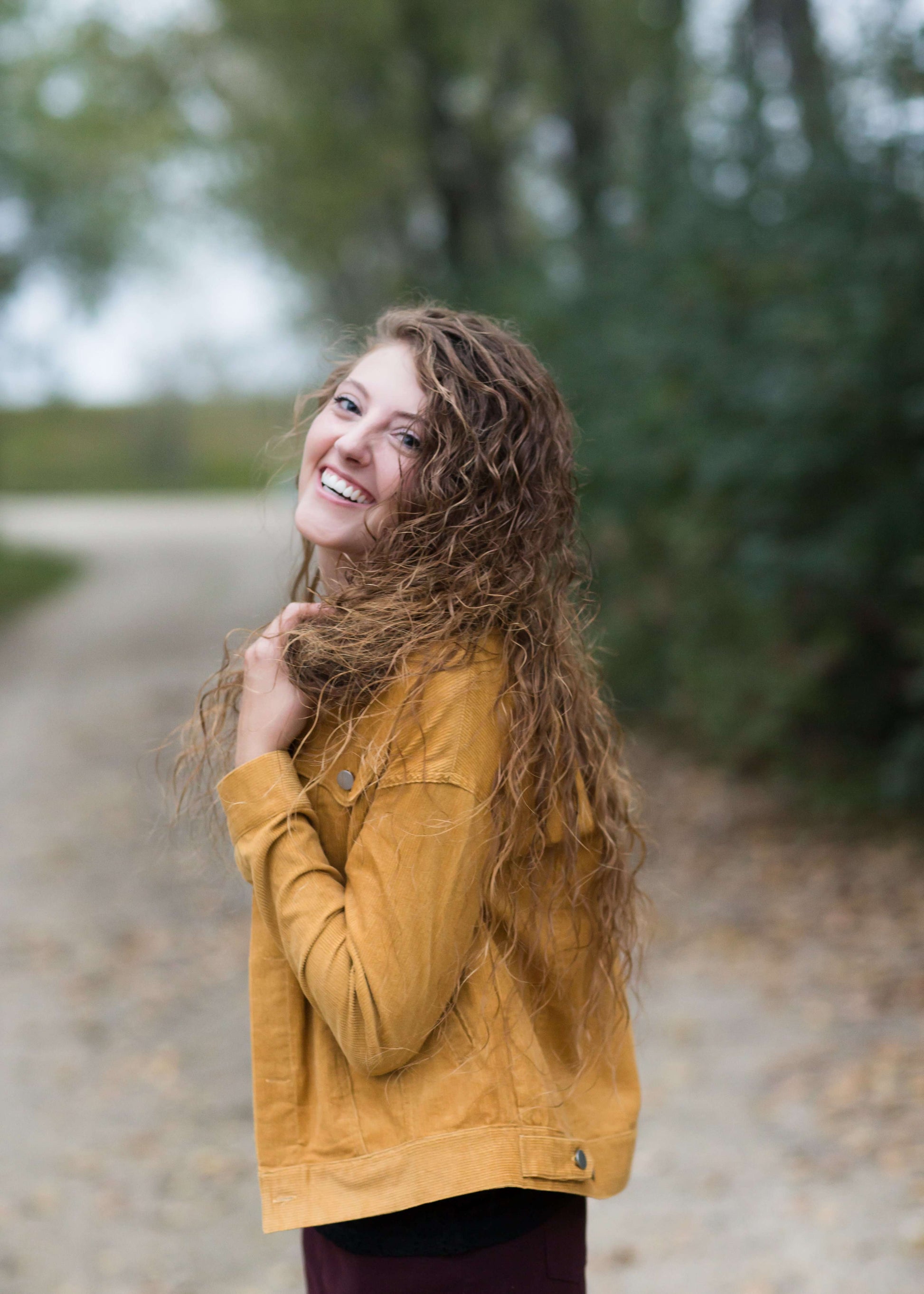 Woman wearing a mustard corduroy button down jacket with pockets.