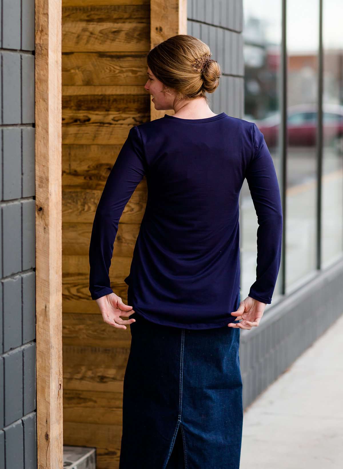 Woman wearing a long sleeve tee that is perfect for layering. It is a stretch material v-neck with a rounded hem. It comes in navy, olive, black, mustard and ivory.